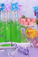 Bottles with drink and sweets on table on bright background