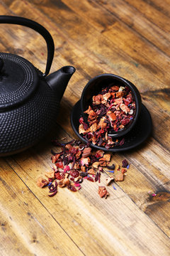 Black teapot, bowl and hibiscus tea on color wooden background