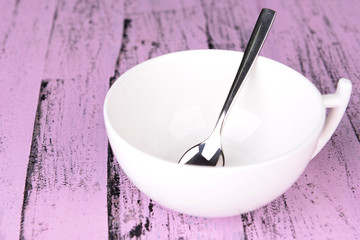 Empty cup with tea spoon on wooden background