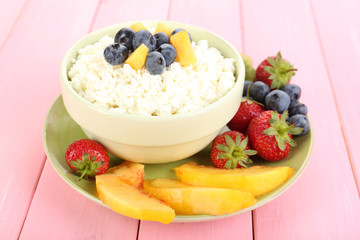 Cottage cheese with fruits and berries in bowl on wooden table