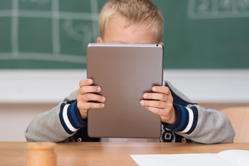 kleiner junge in der schule liest am tablet-pc
