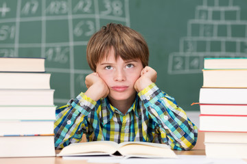 wütender schuljunge zwischen bücherstapeln