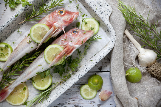 two fresh whole fishes on casserole with aromatic plants