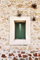 Fototapeta na wymiar Green wooden window on a stone wall