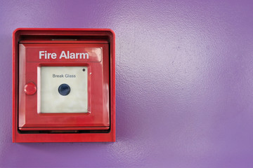 Red box of fire alarm on violet wall
