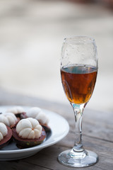 Glass of cognac with Mangosteen standing on a wooden table in su