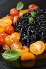 Squid ink coloured tagliatelle with fried tomatoes, close-up
