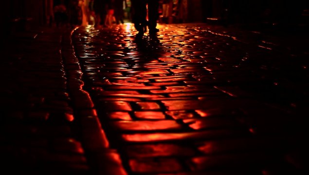 People walking on dark street at night.