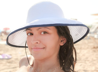 Photo of sexy tanned woman with big white hat on the beach