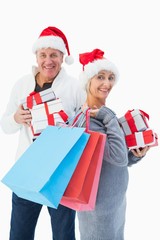 Festive mature couple in winter clothes holding gifts and bags