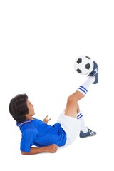 Football player in blue kicking the ball