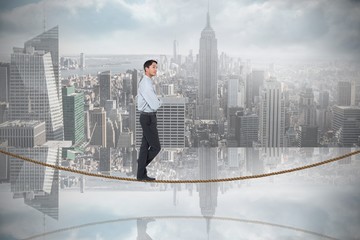 Fototapeta na wymiar Composite image of serious asian businessman on tightrope