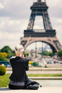 Young woman taking a photo with mobile phone in Paris, France.