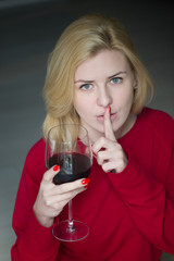 Woman drinking red wine with finger on mouth - addicted