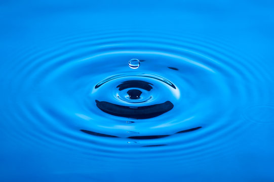 Waves of water caused by the falling droplets with blue lighting