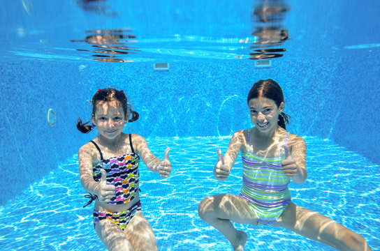 Happy active kids swim in pool and play underwater