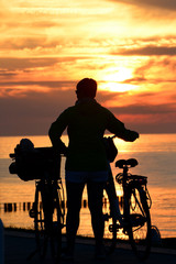 Frau mit Fahrrad genießt Sonnenuntergang