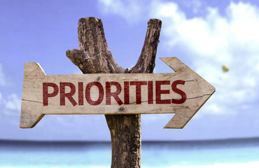 Priorities wooden sign with a beach on background