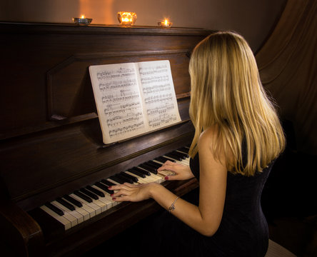 Girl playing the piano by candlelight