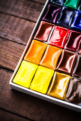Watercolor paints on vintage wooden background close up. Art sup