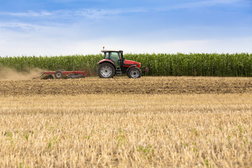 Tractor cultivating wheat stubble field, crop residue.