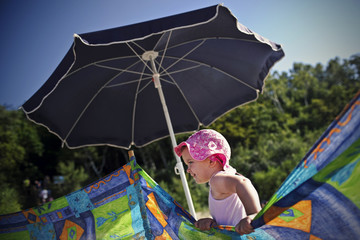 Little girl at beach hiding behind a colorful screen