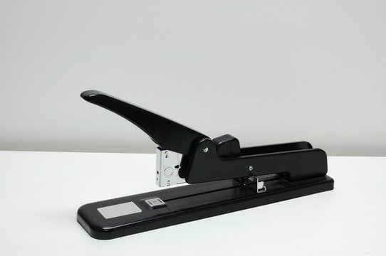 Single heavy stapler on white desk.