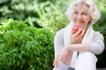 Sportliche Seniorin mit Apfel