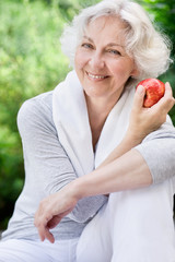 Sportliche Seniorin mit Apfel