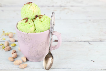 Tasty pistachio ice cream in cup on wooden table
