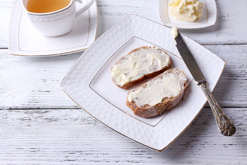 Fresh bread and homemade butter on plate on wooden background