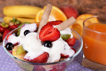 Fresh fruits salad with ice cream in bowl and juice