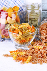 Colorful pasta in glass jars on wooden background