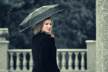 Happy young fashion woman with umbrella in the rain