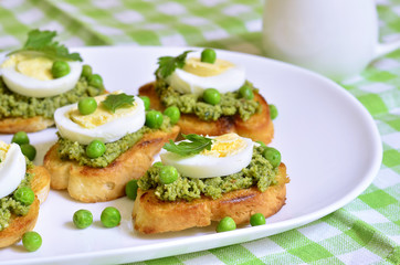 Toasts with basil pesto,eggs and green peas.