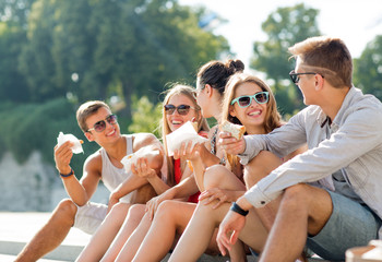 group of smiling friends sitting on city square