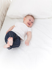 Funny little baby girl on white bed