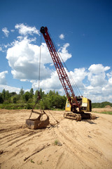 Excavator standing on sand near forest on summer day