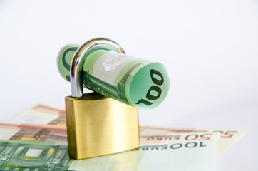 Euro Geldschein gerollt mit Vorhaengeschloss auf Geldscheinen