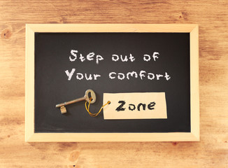 the phrase step out of your comfort zone written on blackboard