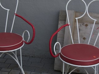 Designerstühle im Stil der Fünfzigerjahre aus weißem Stahlrohr mit roter Sitzfläche im Sommer...