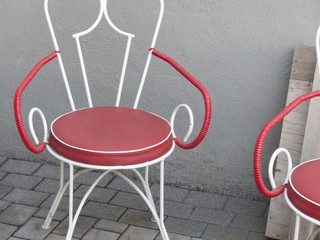 Designerstühle im Stil der Fünfzigerjahre aus weißem Stahlrohr mit roter Sitzfläche im Sommer...