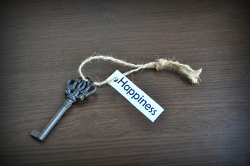 Key on the table with a note written on it key to happiness