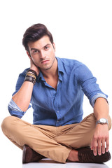 serious young man sitting on white background