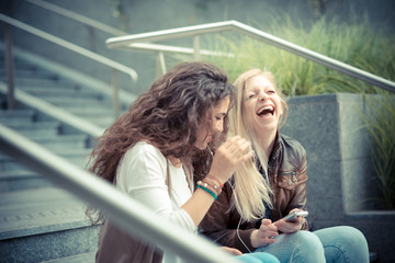 blonde and brunette beautiful stylish young women using smart ph