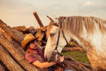 man in hat on a lumbers and white horse above