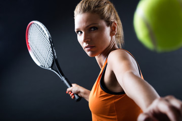 Portrait of beautiful woman playing tennis indoor.
