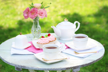 Coffee table with teacups and tasty cakes in garden