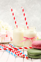 Milk in bottles with paper straws on table