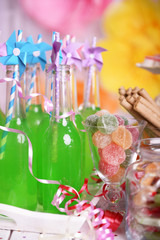 Bottles of drink with straw and sweets on decorative background